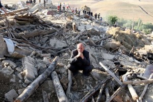 An Iranian resident from the village of Baje-Baj, near the town of Varzaqan, stands on top of the rubble of his destroyed home on 12 August  AFP PHOTO / ATTA KENARE 