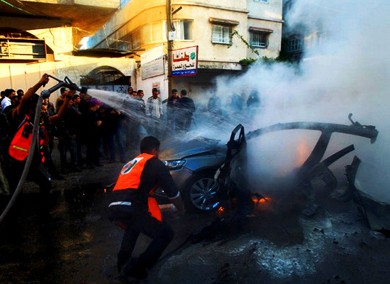 Palestinians extinguish fire from the car of Ahmaed Jaabari, head of the military wing of the Hamas movement, the Ezzedin Qassam Brigades, after it was hit by an Israeli air strike in Gaza City on November 14, 2012. (AFP PHOTO / MAHMUD HAMS)(